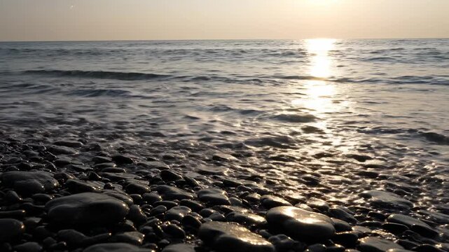 Wave washing onto pebble beach at sunset