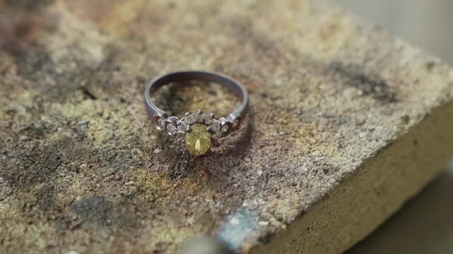 Handcrafted silver ring with yellow stone and diamonds on jeweler workbench