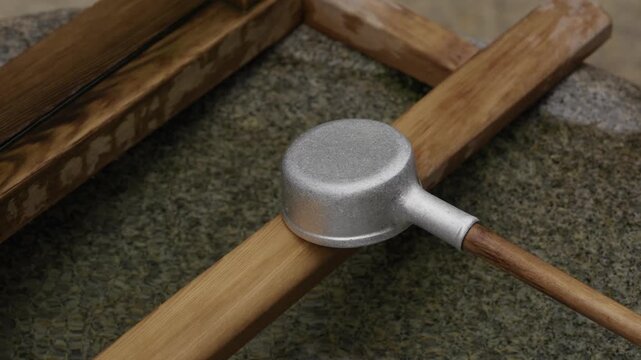 Aluminium ladle resting across a bamboo water basin at a temizuya purification fountain at a Japanese shrine