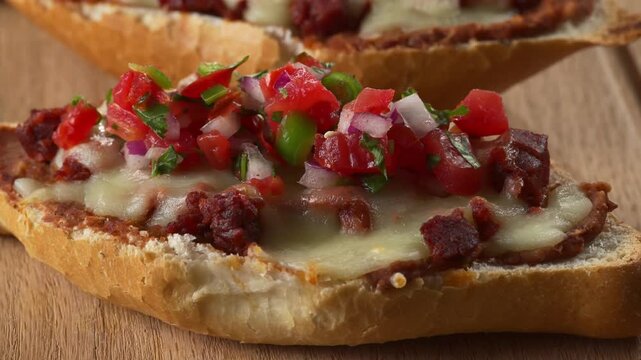 Freshly baked bolillo toast with refried beans, cheese and chorizo topped with fresh salsa