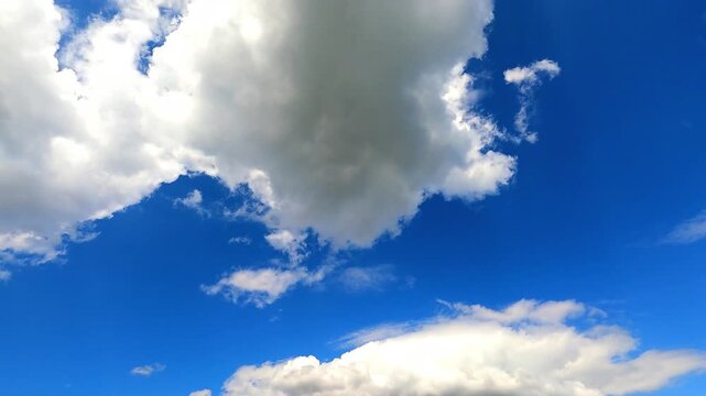 A beautiful time-lapse showing a view of a clear and bright blue sky sprinkled with slowly moving white cumulus clouds.