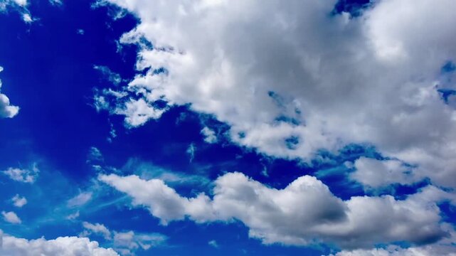 The time-lapse reveals the charm of a bright blue sky adorned with billowing white clouds (cumulus) moving dynamically and dramatically.