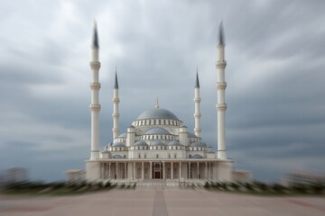 Fototapeta premium Grand mosque with tall minarets and domes under cloudy sky.
