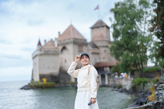 Woman Tourist Explore Chateau de Chillon, Montreux, Switzerland in Summer. Traveler Visit the Historic Medieval Castle on Lake Geneva, Famous European Tourist Attraction and Europe Travel Destination