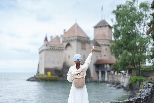 Woman Tourist Explore Chateau de Chillon, Montreux, Switzerland in Summer. Traveler Visit the Historic Medieval Castle on Lake Geneva, Famous European Tourist Attraction and Europe Travel Destination