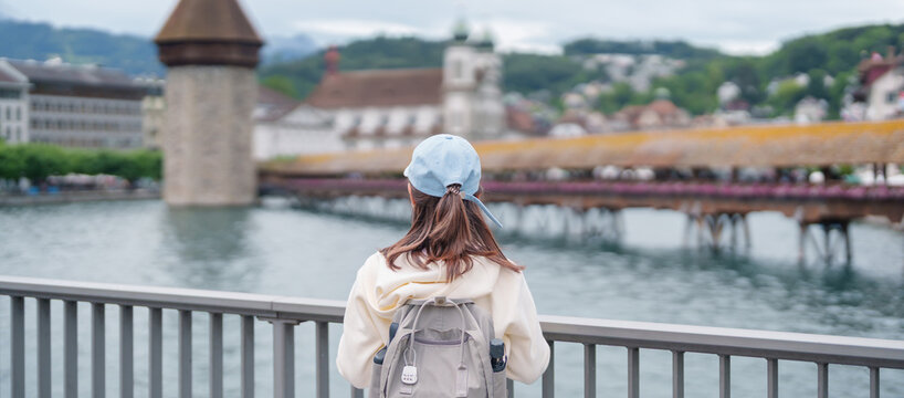 Woman Tourist Explore Lucerne, Switzerland in Summer. Traveler Visit Chapel Bridge and Water Tower on Reuss River. Famous European Landmark, Popular Tourist Attraction and Travel Destination in Europe