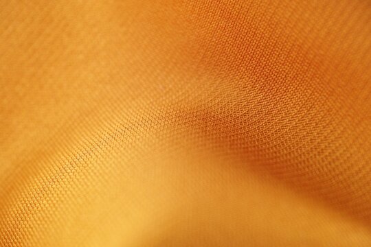 Close Up of Soft Golden Yellow Fabric Texture with Woven Pattern and Elegant Folds