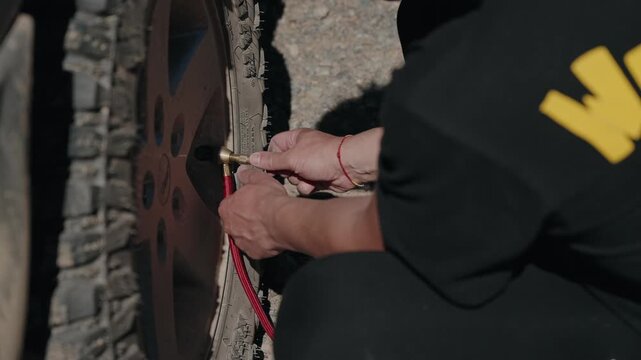 Close view of hands fitting a brass inflator chuck to an off road tire valve