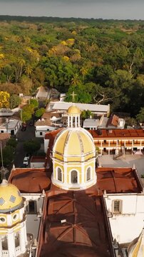 Vertical ascending pullback aerial shot of Parroquia de San Miguel Arc&aacute;ngel in the historic center of Comala, Colima, Mexico revealing the iconic domes and surrounding colonial architecture
