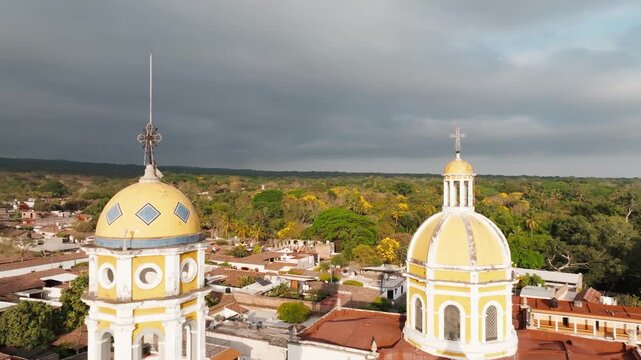 Vertical aerial pullback of Parroquia de San Miguel Arc&aacute;ngel and Plaza Principal de Comala in the historic center of Comala, Colima, Mexico, overlooking the iconic church facade