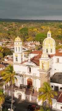 Vertical aerial orbit of Saint Michael Archangel Church facade in downtown Comala, Colima, Mexico