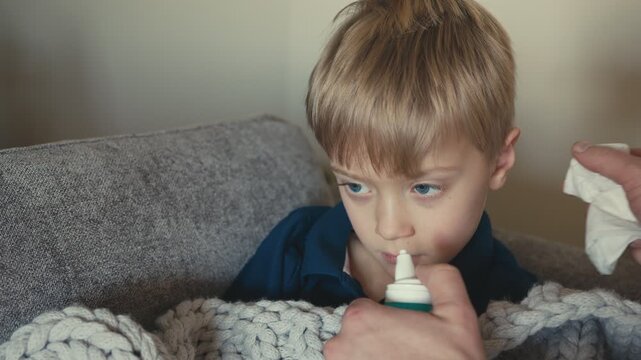 Sick child receiving nasal spray treatment from parent
