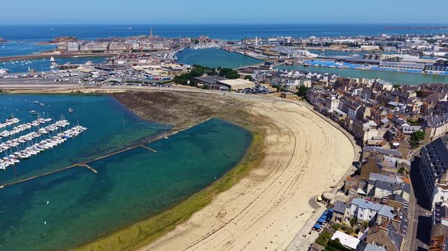 Plage des Bas Sablons curves beside Port des Bas Sablons with Intra-Muros beyond in Saint-Malo, Ille-et-Vilaine, Brittany, France, revealing the Emerald Coast, drone forward flyover.