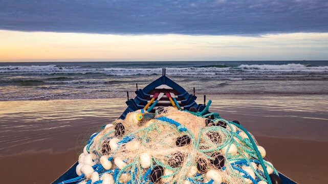Pesca da tainha em Florianopolis p&ocirc;r-do-sol com nuvens carregadas de chuva e o barco ancorado na areia da praia do Santinho Ingleses ilha de Florian&oacute;polis Santa Catarina Brasil 