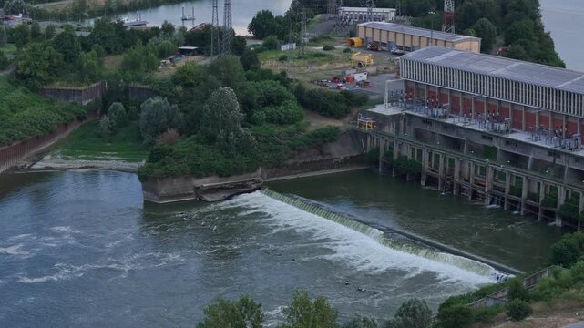 Drone forward flyover above the Carlo Bobbio Hydroelectric Power Plant and spillway on the Po River at Isola Serafini, Monticelli d'Ongina, Piacenza, Emilia-Romagna, Italy, highlighting infrastructure