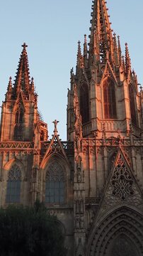 A detailed vertical view of the Cathedral of the Holy Cross and Saint Eulalia in Barcelona, Spain, at sunset
