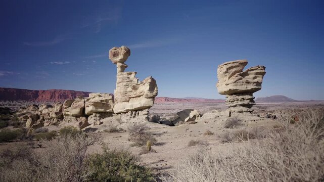 Expansive panoramic shot reveals bizarre, wind-carved rock formations in Ischigualasto Provincial Park under clear blue sky, highlighting arid desert landscape and rugged geology.