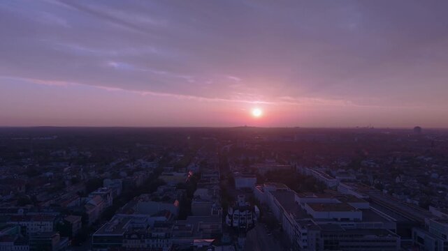 Observing Berlin's urban landscape and skyline from above at dusk, with warm sunset colors in a cloudy sky. Fabulous aerial view fly reverse drone panorama speed ramp hyper motion time lapse