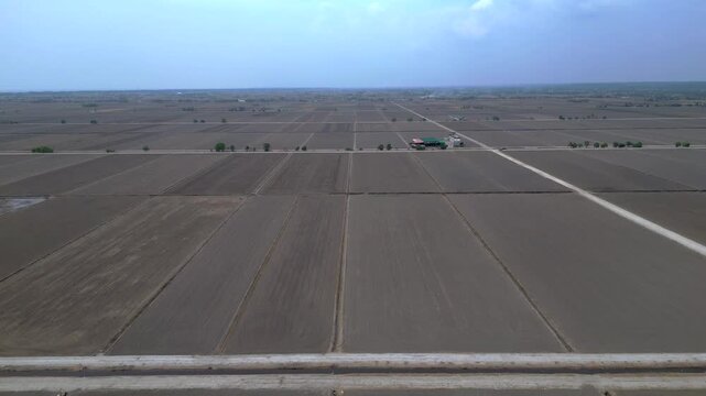 Vast aerial view of Sekinchan Infinity Harvested rice fields featuring barren rectangular plots, paths, and a distant building, preparing for cultivation. Fantastic aerial view fly reverse drone pano