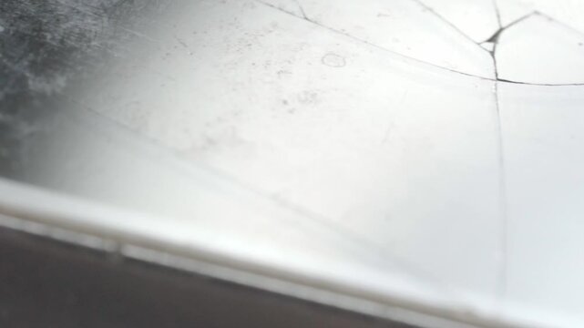 Macro close up of cracked smartphone screen showing damaged glass surface. Mobile phone display with visible fracture lines and broken glass captured in detailed view