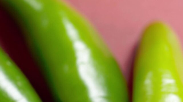 Extreme close up of fresh green chili peppers revealing smooth glossy surface texture and vibrant natural color. Detailed food background ideal for cooking and healthy eating concepts
