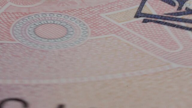 Spinning macro view of banknote security features and printed currency details. Closeup reveals intricate patterns, embossed elements and anti counterfeiting design on paper money.