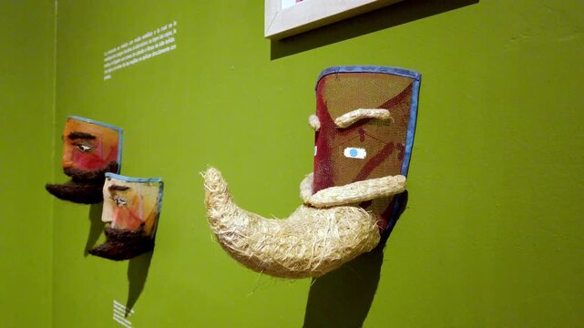 Closeup of handcrafted decorative face mask with woven beard mounted on museum wall showcasing traditional folk art, textured craftsmanship and cultural design.
