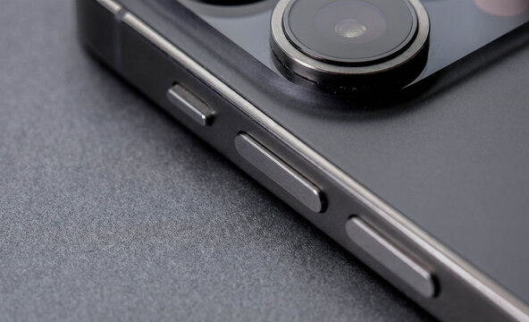 Close-up of a smartphone's side buttons and camera module, highlighting the sleek design and modern features of the device against a dark background.