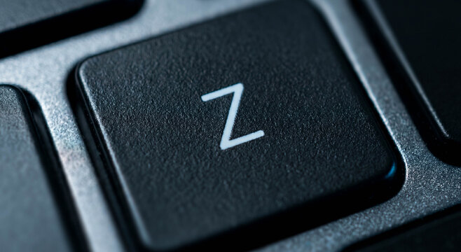 Close-up of a black computer keyboard key featuring the letter 'Z'. The texture of the key and its surroundings are highlighted, showcasing details.
