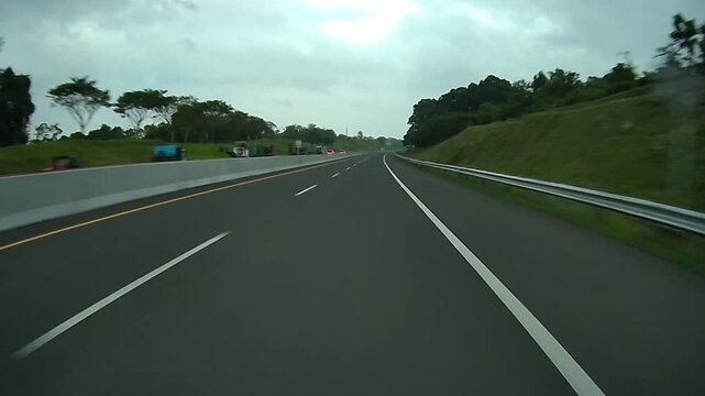 Rear Dashcam Driving Along Madiun Toll Road with Green Hills Under Overcast Skies in East Java Indonesia