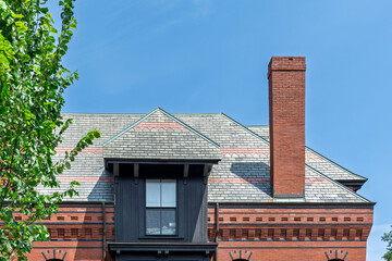 Historic red brick chimney and patterned slate roof with a gabled dormer  © Baharlou