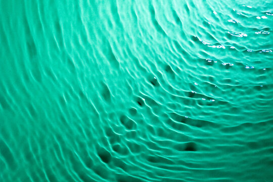 Deep teal water ripples background texturing abstract waves.