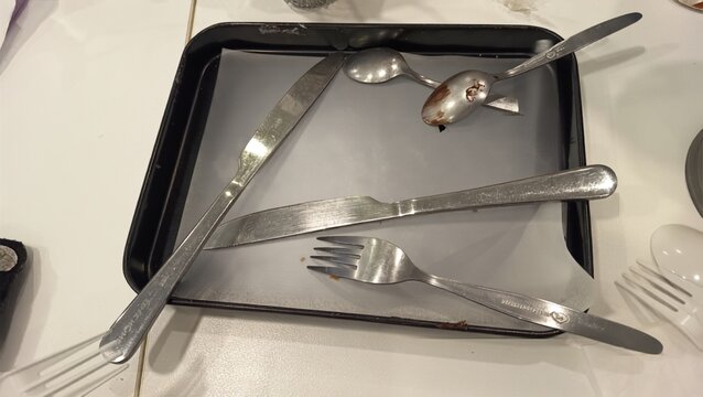 Empty food tray with used fork, knife, and spoon after eating