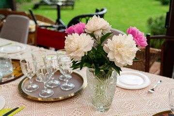 Dining table with peony centerpiece and glassware tray © obsidianium