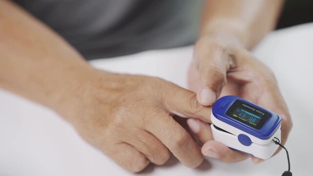 Close up of a caregiver using a pulse oximeter to measure blood oxygen saturation and pulse rate for a senior, representing home healthcare, vital signs monitoring, preventive care, and healthy aging.