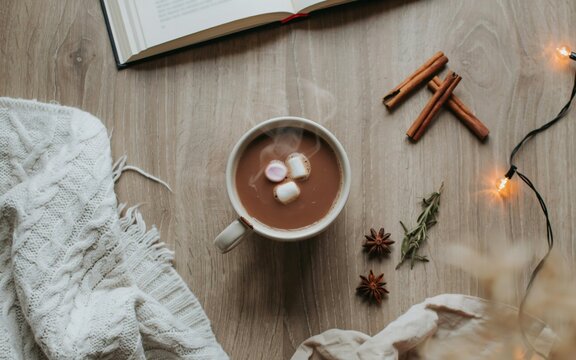 Cozy winter flat lay with hot chocolate mug, knitted sweater, and sparkling lights. Cozy Hot Chocolate with Marshmallows and Cinnamon.