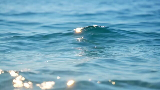 Shimmering water nature blue ocean wave surface calm sunlight reflection serene seascape with gentle sea wave and soft light reflection creating calm summer mood, sparkling clear water texture