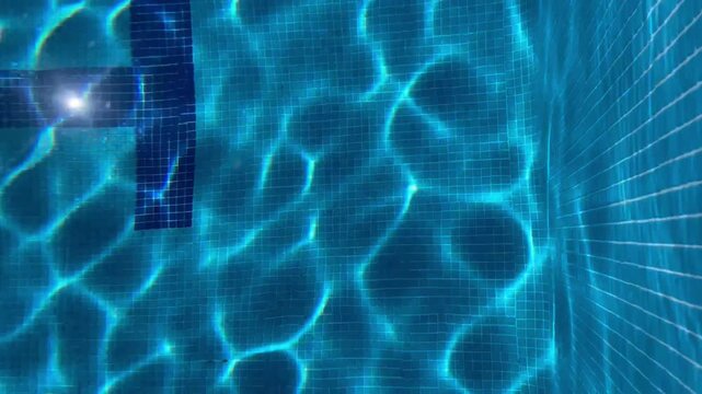 Abstract underwater pool tiles with shimmering blue caustic light