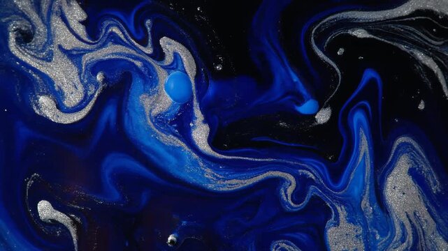 Deep sapphire blue and silver ink blooms through clear liquid, forming elegant marbled veinlike patterns under dramatic side lighting with glossy cinematic macro fluid motion.