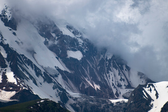Snowy rocky mountain ridge shrouded in dense fog and clouds in Georgia with copy space