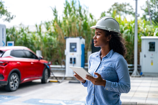 Engineer standing inspection electric vehicle (EV) charging station reflects the growing adoption of eco-friendly environment technology and sustainable in the renewable energy sector.