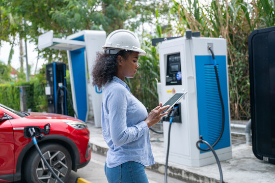 Engineer standing inspection electric vehicle (EV) charging station reflects the growing adoption of eco-friendly environment technology and sustainable in the renewable energy sector.