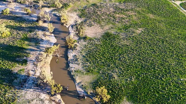 Aerial video flying over the Pilliga landscape at sunset in NSW, Australia. Warm golden light illuminates the expansive bushland and rural landscape