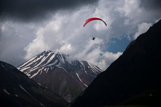 Paraglider flying over snow covered mountains under storm clouds in Gudauri Georgia with copy space