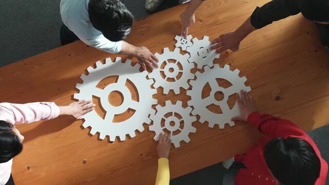 Top view of business people gathering white gear together at meeting table. Group start up team in casual cloth working together connecting cog together. Cooperate, teamwork,togetherness. Convocation.