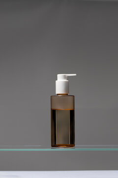 Plastic cosmetic bottle with clean skincare oil at grey background