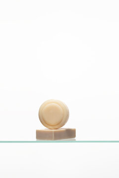 A minimalist stack of two artisanal soap bars-one round, one rectangular-showcasing natural, uncolored tones. Represents a simple, gentle skincare and personal hygiene routine.
