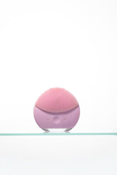Single purple silicone facial massager and cleanser standing on a glass shelf. Ideal for close-up shots of beauty technology and personal care products.