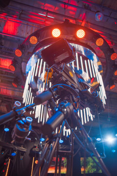 Professional video camera on tripod with stage neon light installation in TV studio with copy space