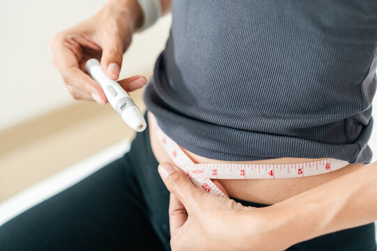 Woman injecting a weight loss pen into her abdomen for diet control. Concept of obesity treatment, GLP-1 medication and slim body goals.